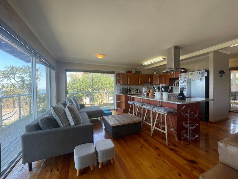 Spacious open-plan living and kitchen area featuring hardwood floors, a central kitchen island with stone countertops, and large sliding doors leading to a balcony.