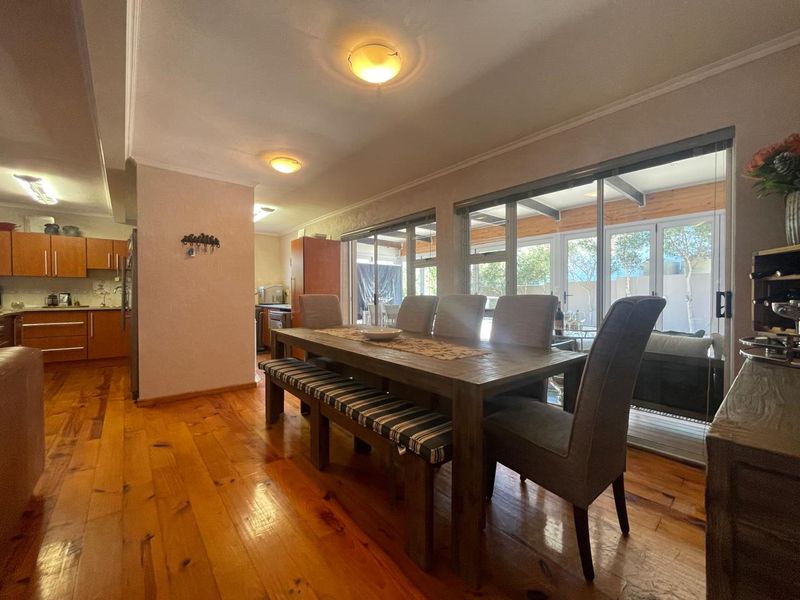 Open plan dining area featuring warm hardwood flooring, crown molding, and large sliding glass doors that provide seamless access to the outdoor patio space.