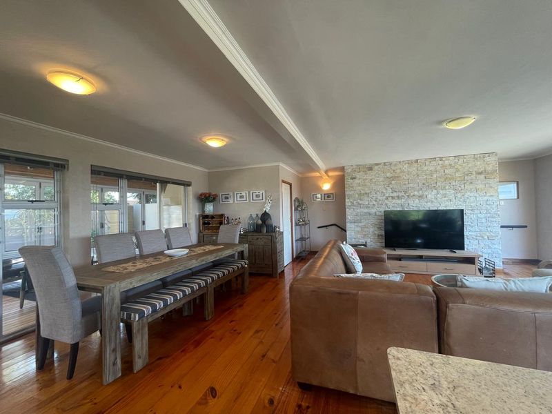 Spacious open-plan living and dining area featuring warm timber flooring, a prominent stone feature wall, and large sliding doors providing natural light.