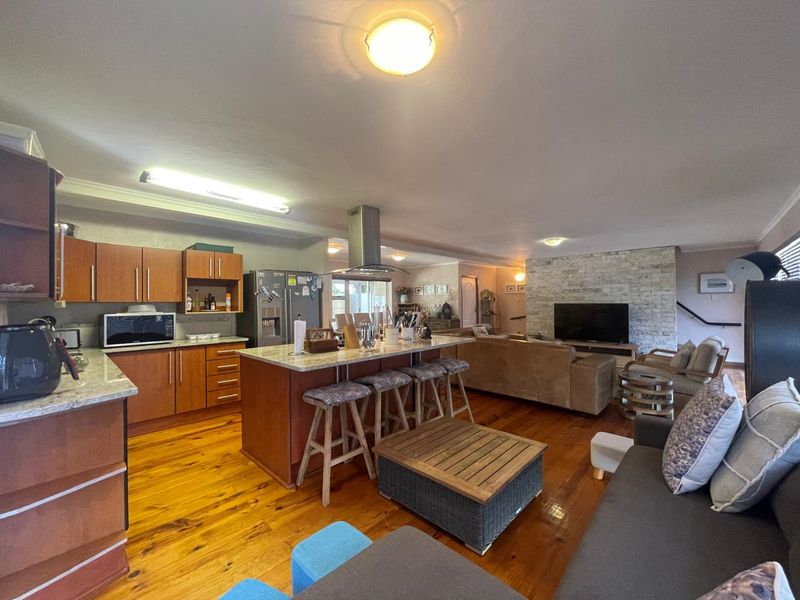 Spacious open-plan living area featuring a modern kitchen with stone countertops, a central island, and a striking stone feature wall in the lounge.