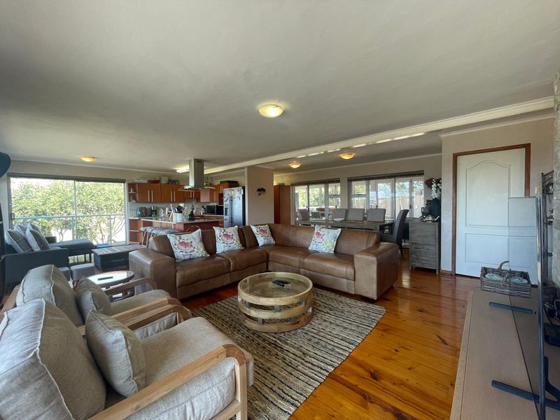 Spacious open-plan living area featuring polished hardwood floors, a modern kitchen with integrated cabinetry, and seamless flow to the outdoor patio through sliding doors.