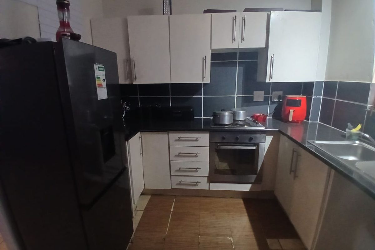 Compact kitchen featuring white cabinetry, dark granite countertops, stainless steel oven and hob, and a tiled backsplash. Requires floor tile repairs.