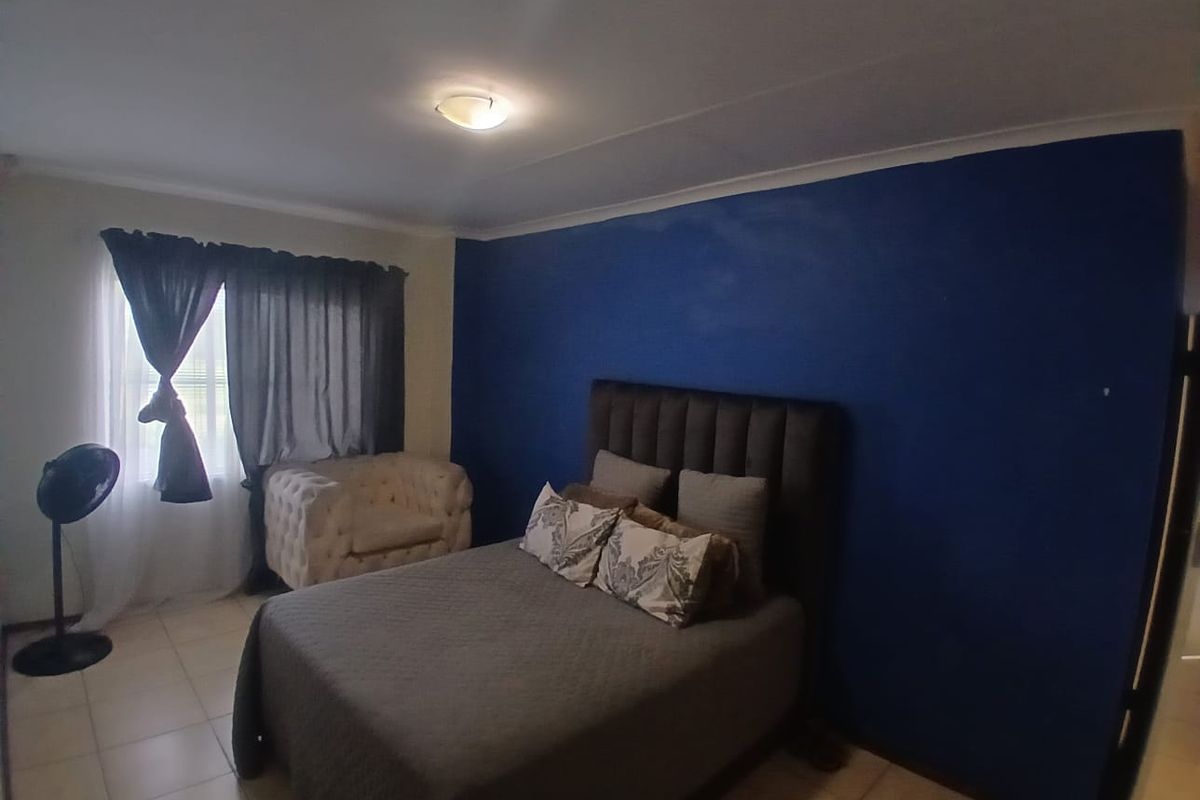 A bedroom featuring tiled flooring, a coved ceiling, and a bold blue accent wall.