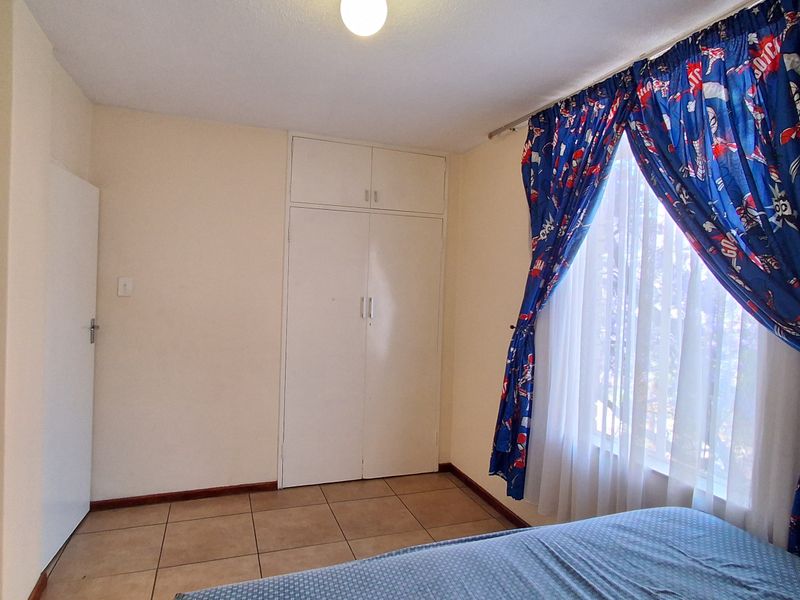 A bedroom featuring tiled flooring and built-in cupboards, providing functional storage space.