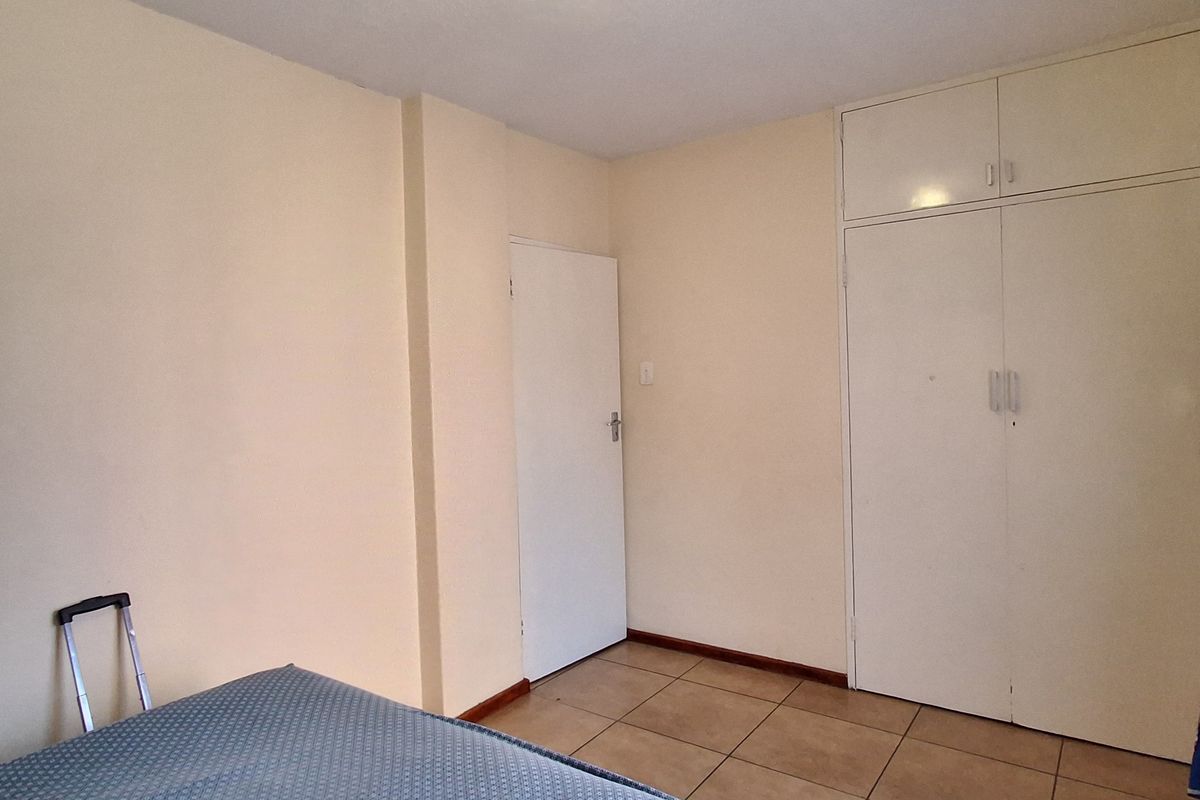 A functional bedroom featuring tiled flooring and built-in cupboards, providing essential storage space.