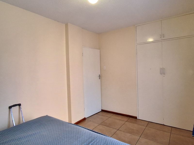 A functional bedroom featuring tiled flooring and built-in cupboards, providing essential storage space.
