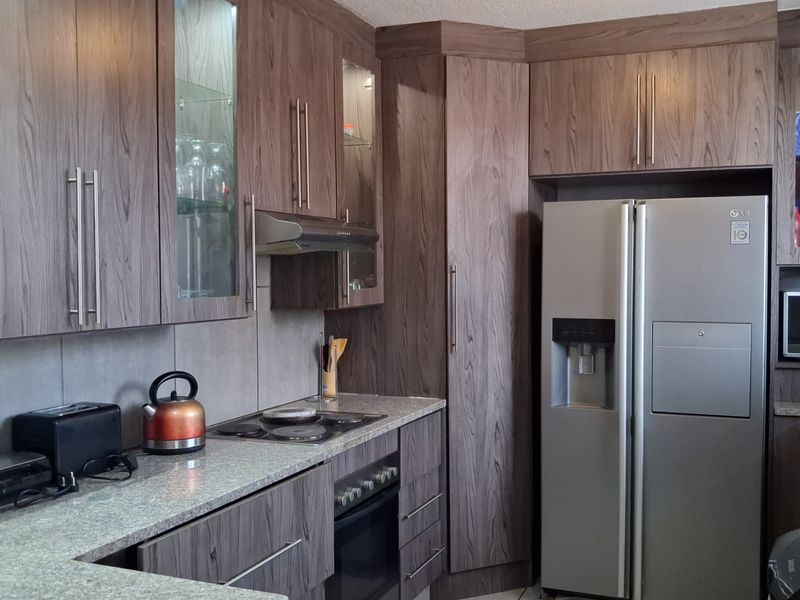 A functional kitchen featuring wood-grain cabinetry, granite countertops, and integrated appliances, offering a clean and practical workspace.
