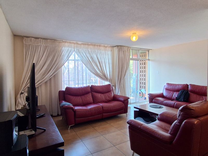 A spacious living room featuring tiled flooring and a large sliding glass door that provides access to an outdoor area.