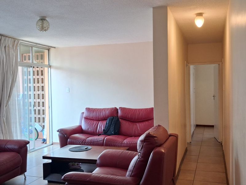 A living room area featuring tiled flooring, ceiling lighting, and a sliding glass door providing access to an outdoor space.