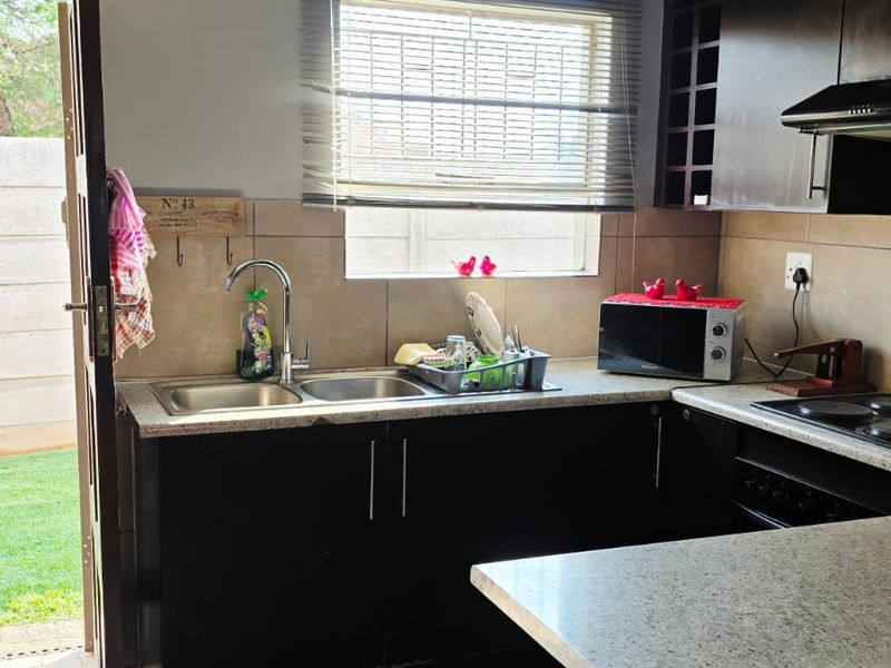 Functional kitchen featuring dark wood cabinetry, granite countertops, double bowl sink, and direct access to the outdoor area.
