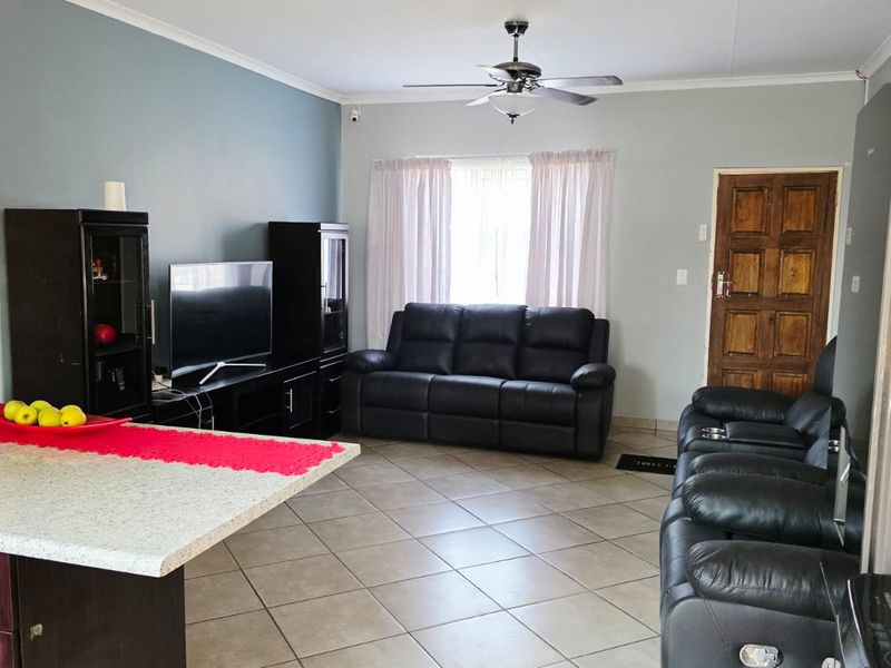 Open-plan living area featuring tiled flooring, a ceiling fan, and a kitchen island, providing a functional and connected space for daily living.