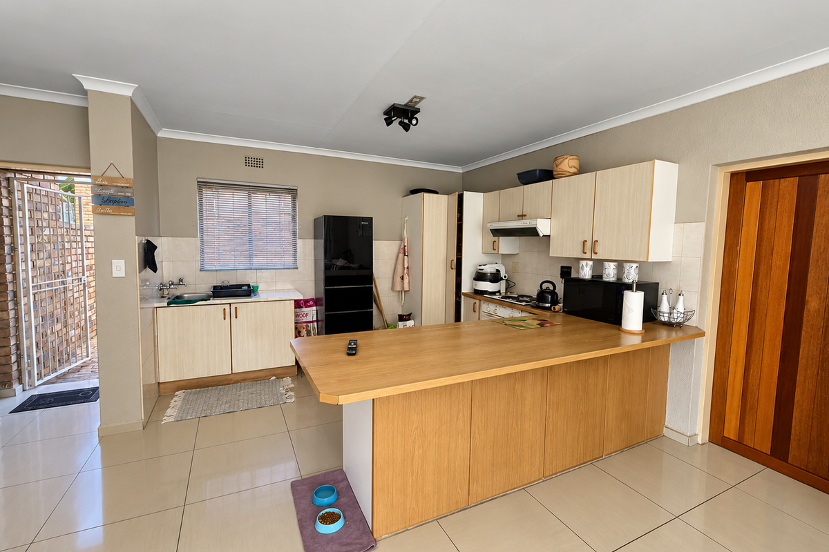 Functional kitchen featuring light wood cabinetry, a breakfast bar, tiled flooring, and a tiled backsplash, offering a practical layout for daily use.