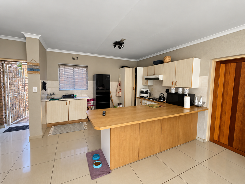 Functional kitchen featuring light wood cabinetry, a breakfast bar, tiled flooring, and a tiled backsplash, offering a practical layout for daily use.