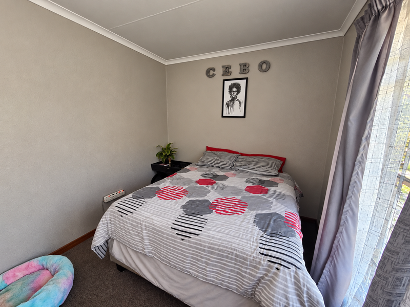 A standard bedroom featuring neutral wall finishes, cove cornicing, and a sliding glass door providing natural light and access to the exterior.