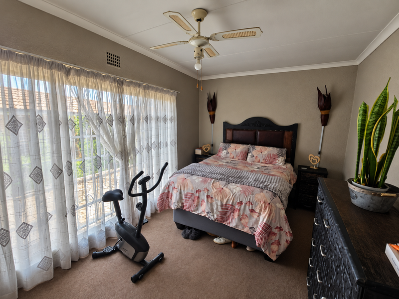 A carpeted bedroom featuring a ceiling fan and a large sliding glass door that provides access to the exterior.