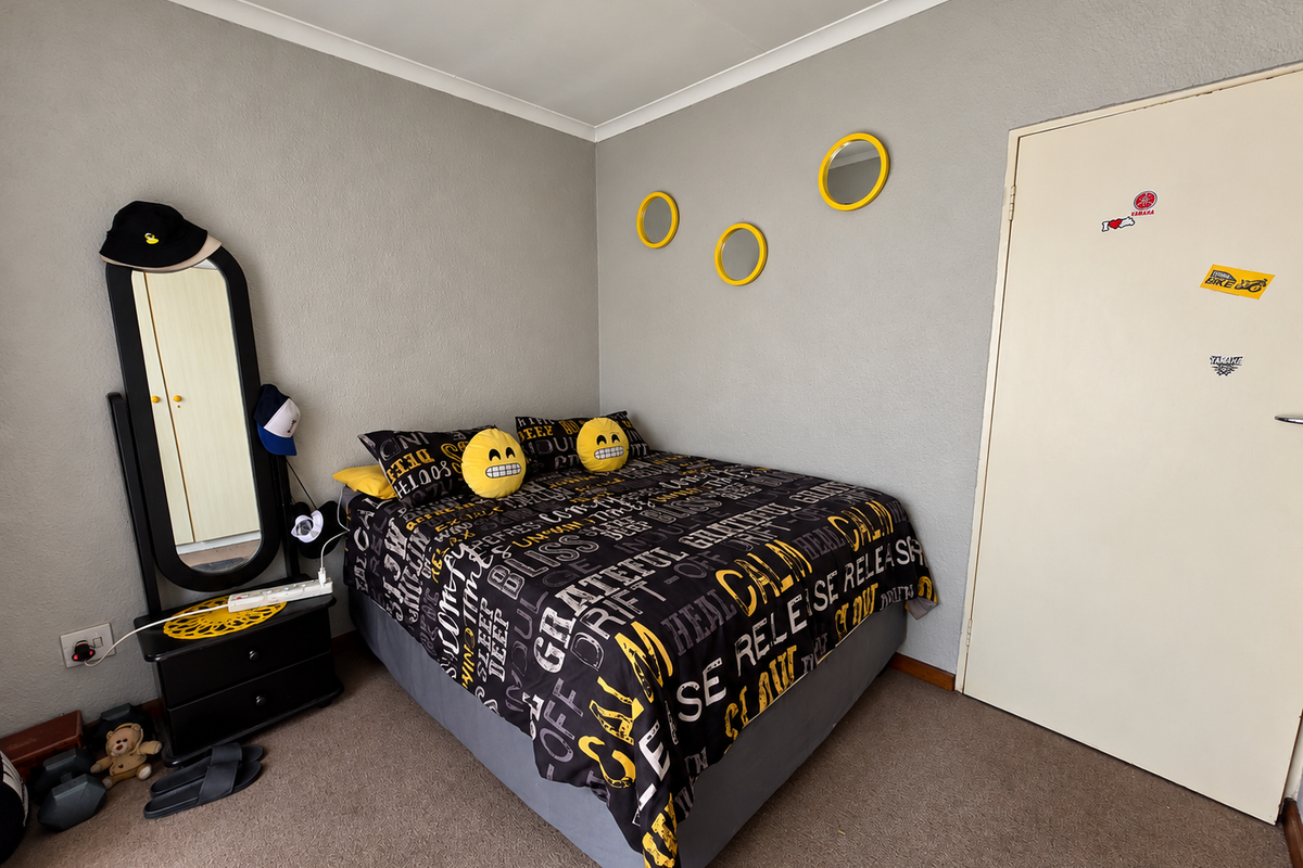 A standard bedroom featuring neutral grey walls, carpeted flooring, and a simple internal door, offering a functional space ready for personalization.