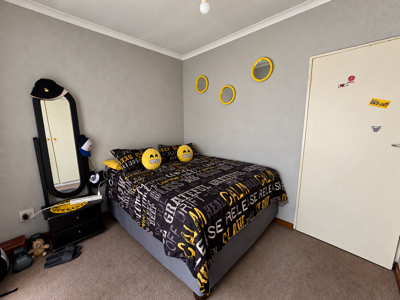 A standard bedroom featuring neutral grey walls, carpeted flooring, and a simple internal door, offering a functional space ready for personalization.