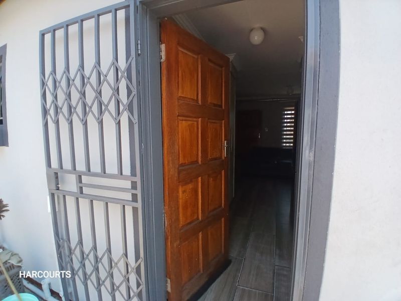 Entrance area featuring a sturdy metal security gate and a traditional timber panel door leading into the home with tiled flooring.
