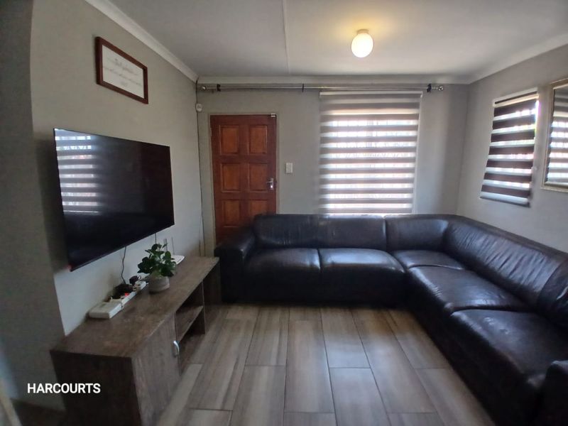 A comfortable living room featuring tiled flooring, modern roller blinds, and a solid timber door, providing a functional and well-maintained space.
