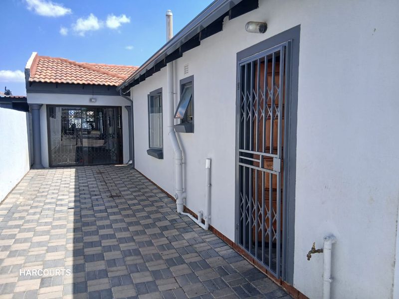 A paved side walkway featuring a security gate, external tap, and access to the rear of the property with a tiled roof.