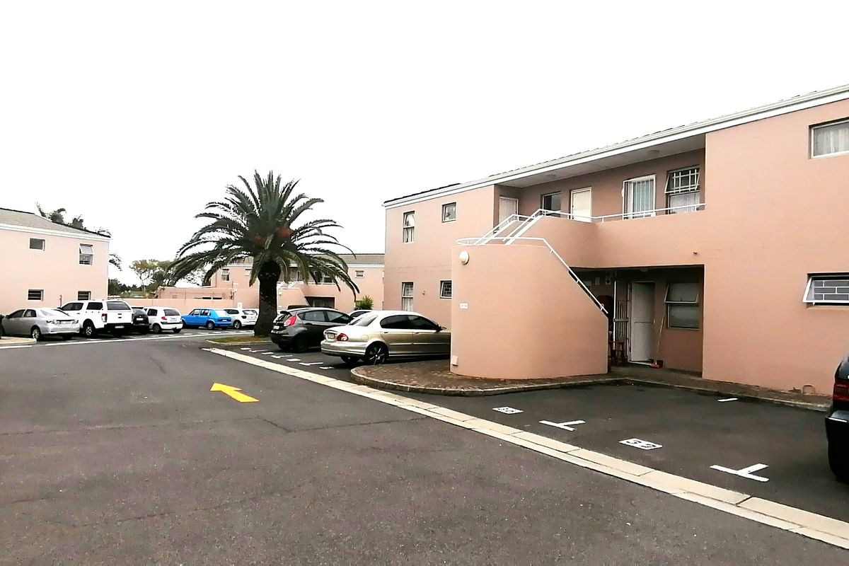 Exterior view of an apartment complex featuring paved parking areas, external staircases, and painted masonry facades.