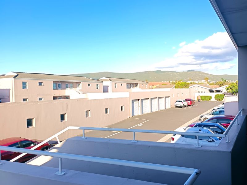 An elevated balcony view overlooking the apartment complex parking area and surrounding neighborhood.