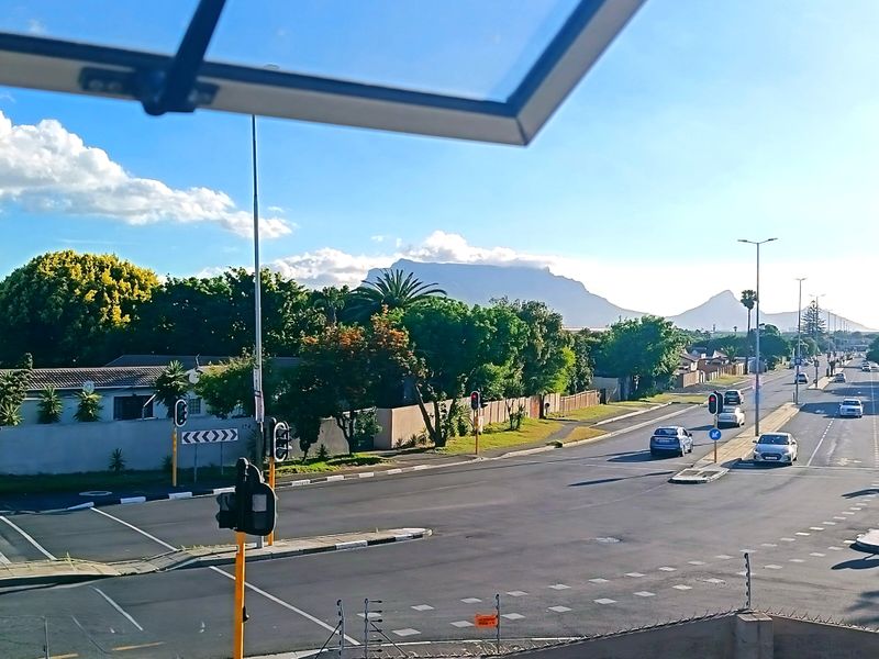 An elevated street view looking out over a suburban intersection with a clear view of Table Mountain in the distance.
