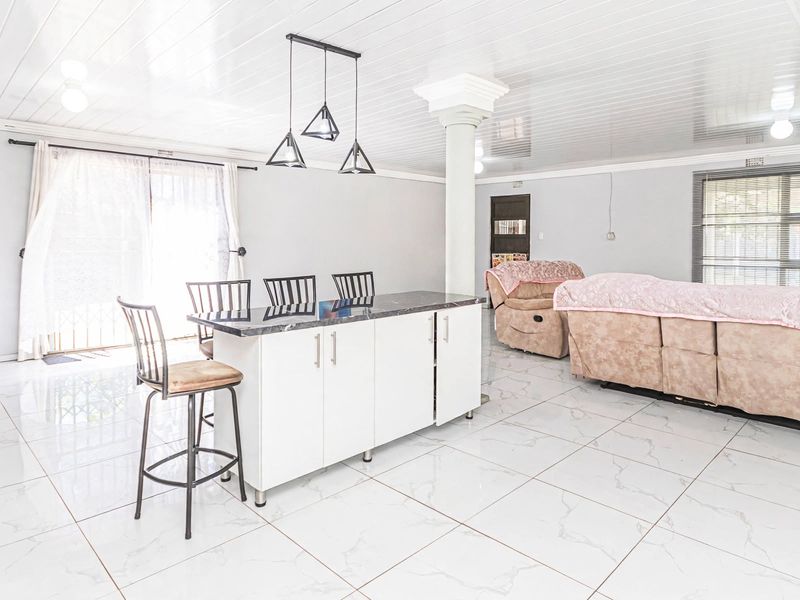 Spacious open-plan living area featuring a modern kitchen island with marble countertop, glossy ceiling, and large sliding glass doors leading to the exterior.