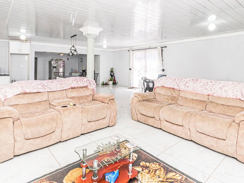 Spacious open-plan living area featuring glossy ceilings, tiled floors, and an integrated kitchen space with ample cabinetry.