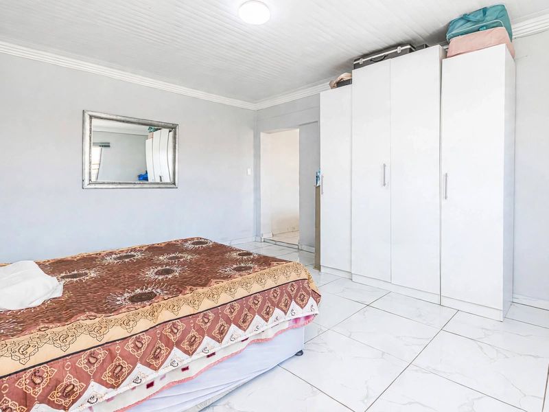 A bedroom featuring white tiled flooring, crown molding, and a built-in wardrobe.