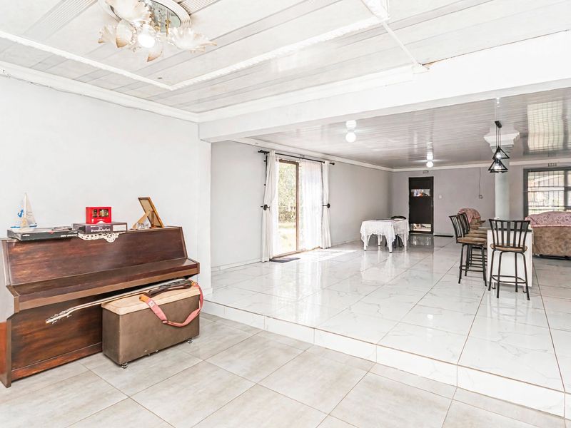Spacious open-plan living area featuring a raised floor section, tiled flooring throughout, and direct access to the outdoors via sliding glass doors.