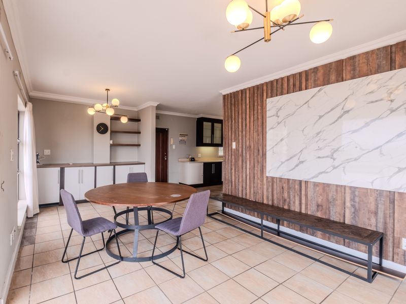 Spacious open-plan living and dining area featuring modern marble-look wall accents, timber-look cladding, tiled flooring, and contemporary ceiling lighting.