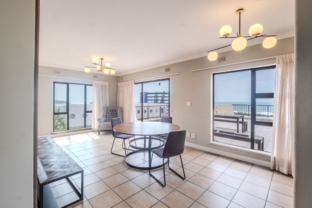 Spacious living area featuring large windows and sliding doors that provide ample natural light and access to an outdoor balcony with ocean views.