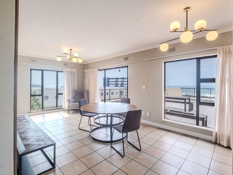 Spacious living area featuring large windows and sliding doors that provide ample natural light and access to an outdoor balcony with ocean views.