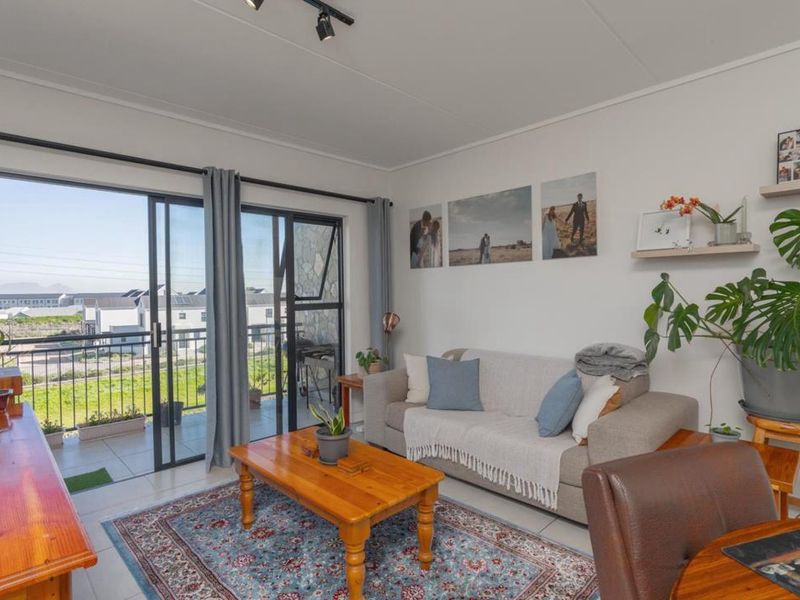 A bright living room featuring tiled flooring, track lighting, and large sliding glass doors that provide access to an outdoor balcony area.