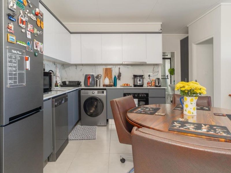 Modern open-plan kitchen featuring sleek two-tone cabinetry, marble-look splashback, and integrated appliances, seamlessly flowing into the dining area.