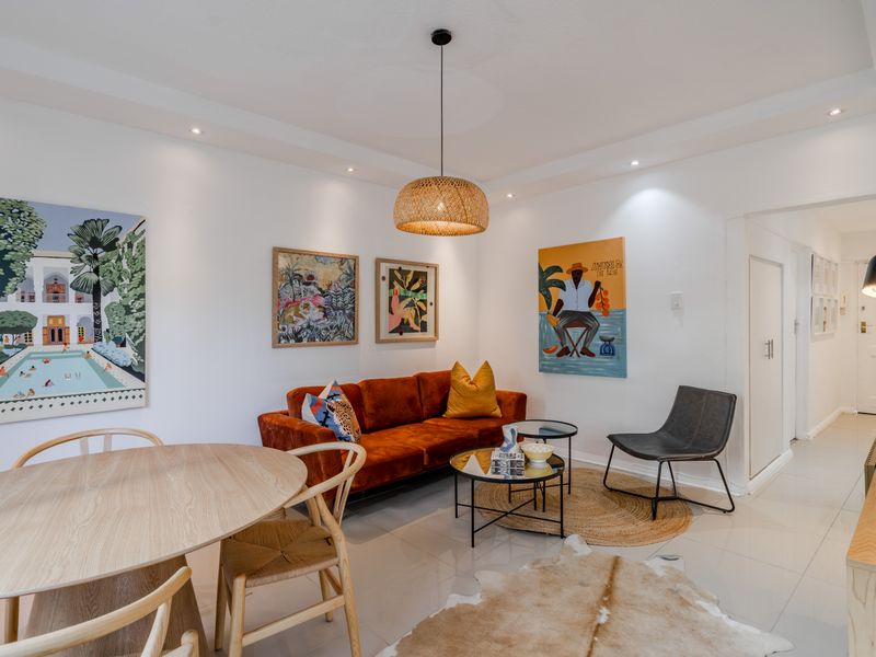 A bright and modern open-plan living and dining area featuring neutral tiled flooring, recessed downlighting, and a clean, contemporary aesthetic.