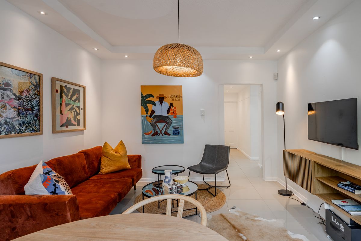 A well-lit living room featuring modern tiled flooring, recessed ceiling lighting, and a decorative cove ceiling design.