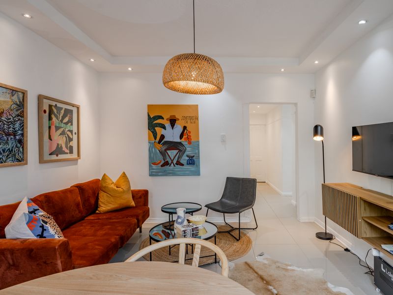 A well-lit living room featuring modern tiled flooring, recessed ceiling lighting, and a decorative cove ceiling design.