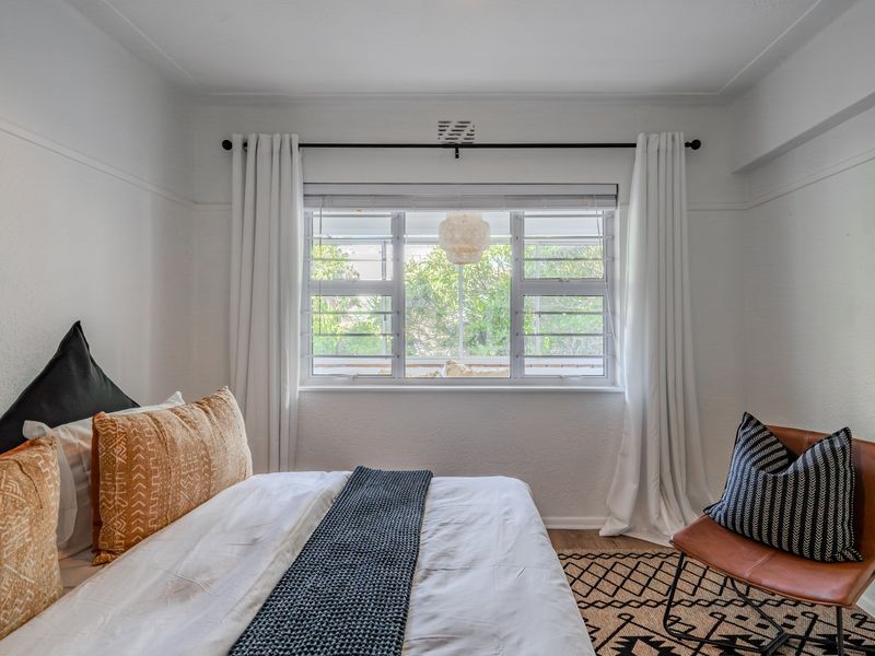 A well-maintained bedroom featuring classic picture rails, decorative cornicing, and functional louvre windows that allow for natural light and ventilation.