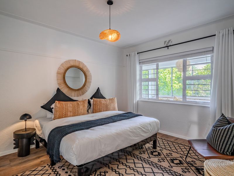 A well-lit bedroom featuring a horizontal sliding window with security bars, classic picture rails, and a modern pendant light fixture.