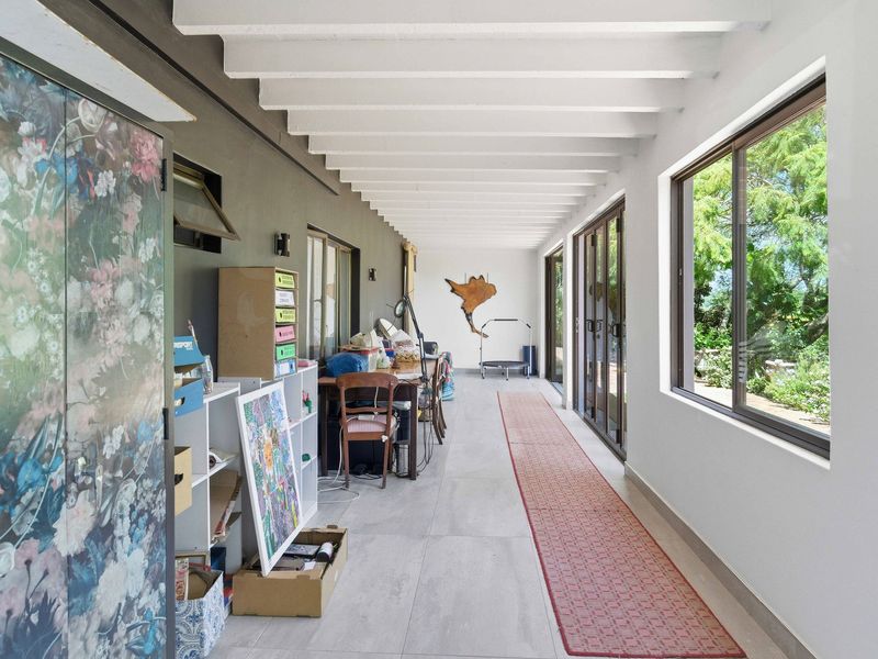 A bright, enclosed patio area featuring exposed beam ceilings, large windows, and sliding glass doors that provide direct access to the garden.