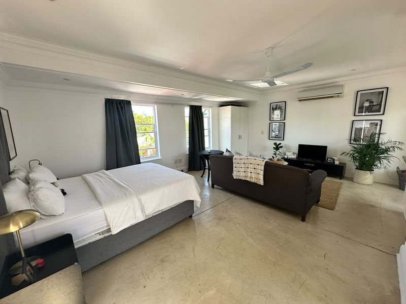 Spacious open-plan studio apartment featuring polished concrete floors, ceiling fan, split-system air conditioning, and built-in storage.