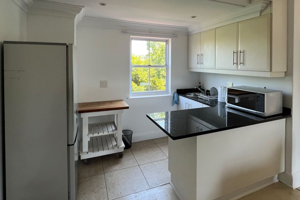 A functional kitchen featuring granite countertops, built-in cabinetry, tiled flooring, and a window providing natural light.