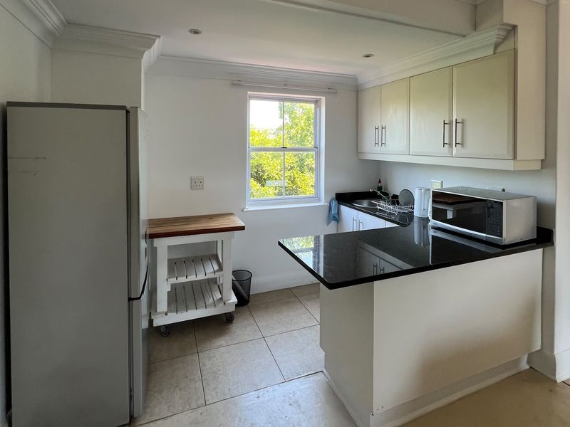 A functional kitchen featuring granite countertops, built-in cabinetry, tiled flooring, and a window providing natural light.