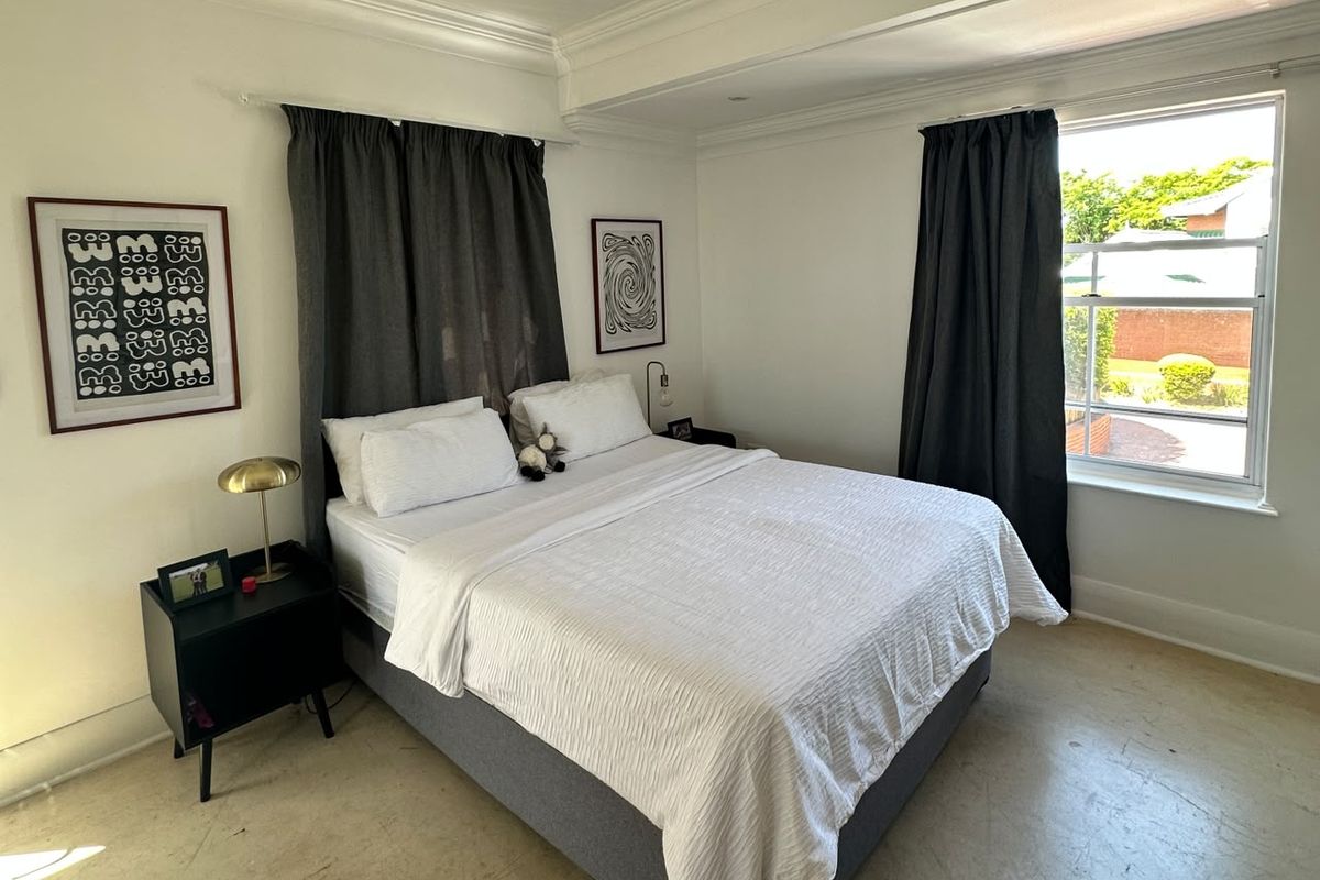 A well-lit bedroom featuring crown molding and a classic sash window, providing a bright and comfortable living space.