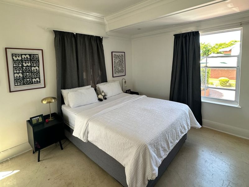 A well-lit bedroom featuring crown molding and a classic sash window, providing a bright and comfortable living space.