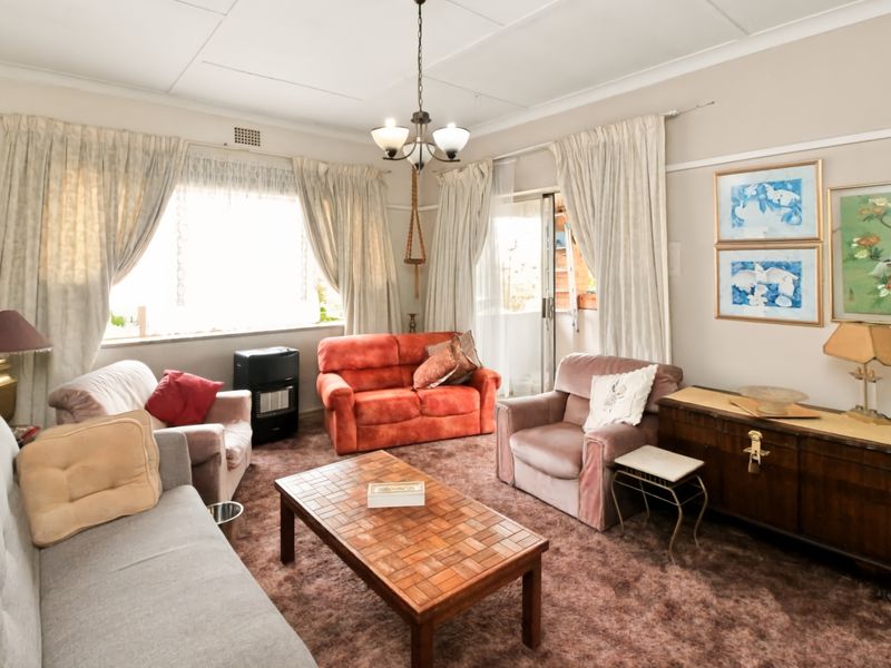 A living room featuring a sliding glass door, picture rails, and dated ceiling tiles, offering a functional space with potential for modernization.
