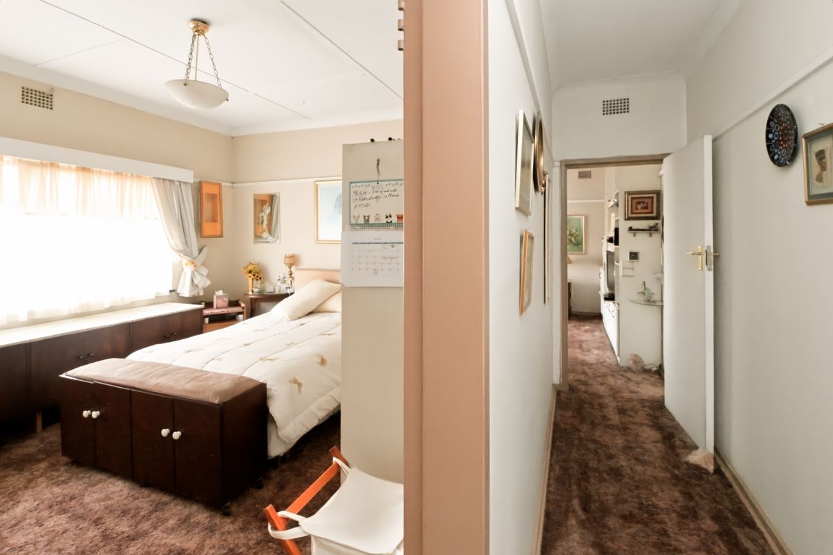 A bedroom featuring built-in cabinetry and a hallway view, showcasing dated finishes and carpeting that would benefit from a modern renovation.