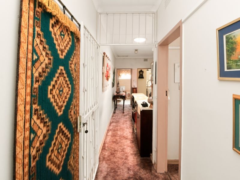 A functional interior hallway featuring carpeted flooring and a security gate, providing access to adjacent rooms within the apartment.